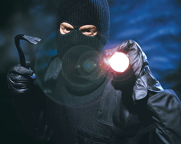 Einbrecher mit Brechstange und Taschenlampe